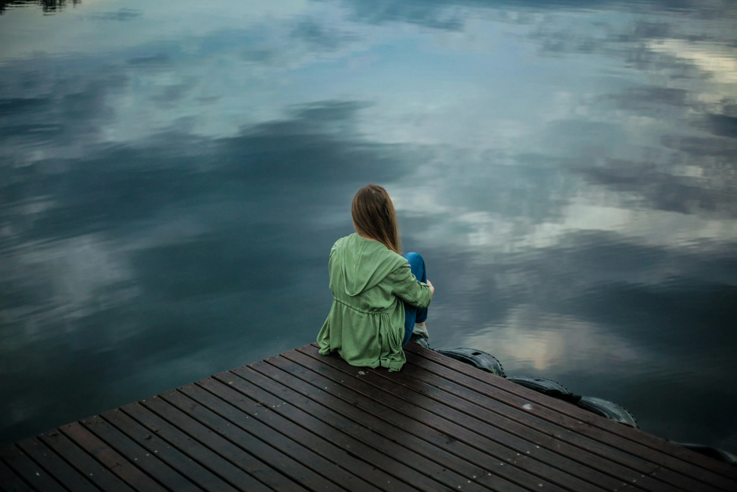 woman sitting on dock: normal to be sad about reaching menopause