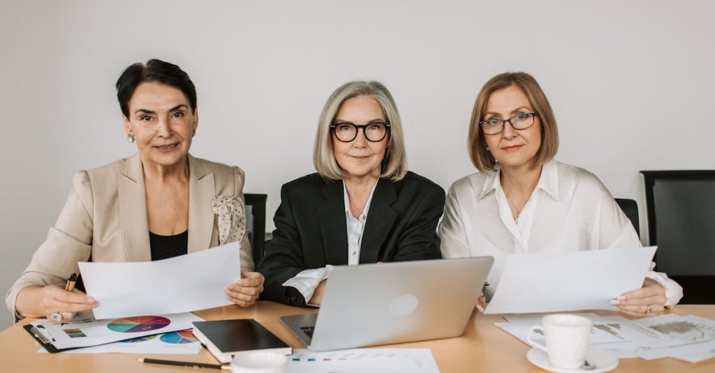 Three senior women discussing business strategies at a modern office table.